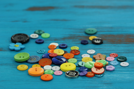 Bright colored haberdashery buttons on a rustic blue wooden backgroundの写真素材