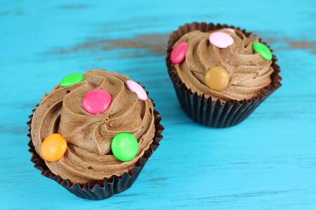 Two chocolate cupcakes on a turquoise wooden backgroundの写真素材