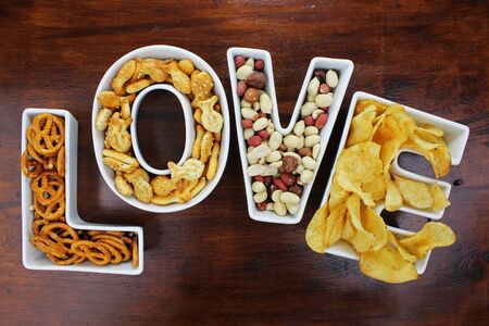 Love snacks Snacks in Love letter bowls on dark wooden backgroundの写真素材