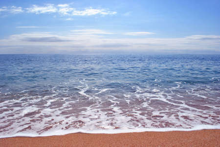 The sea wave with foam is rolled on a sandy beach.