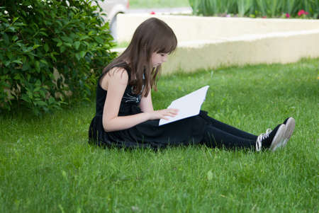 teenager girl reading a book in the parkの写真素材
