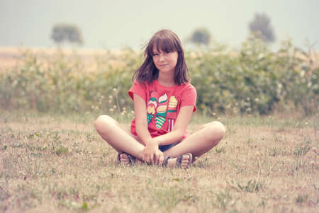 teen girl sitting on the grassの写真素材