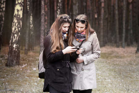 girl walking in the autumn forest and looking at phoneの写真素材