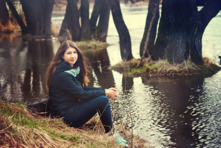 The girl sits on the river bankの写真素材