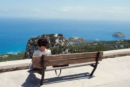 The girl rests on a bench and admires the seaの写真素材