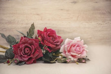 Bouquet of three snow roses on a wooden background with space for congratulationsの写真素材
