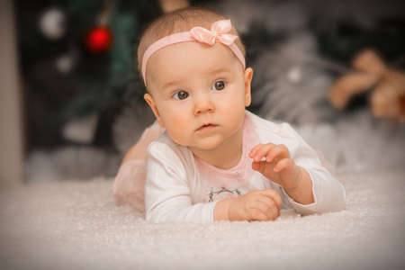 close-up baby girl lying under a christmas treeの写真素材