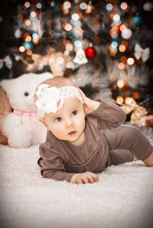 portrait little baby is lying on the tummy under the Christmas tree against the background of soft toysの写真素材