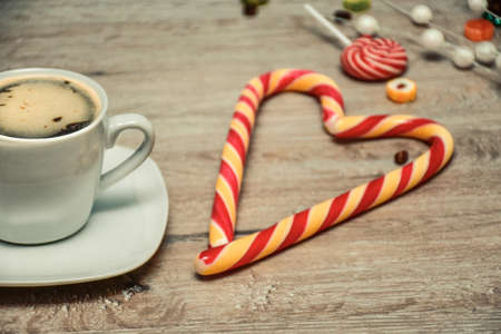 cup of coffee and candies on wooden background