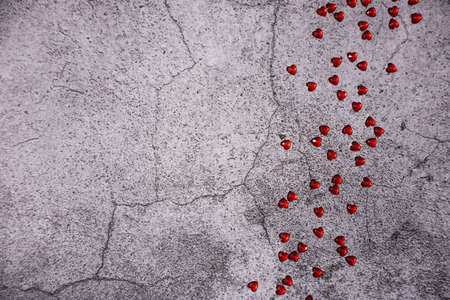small red hearts scattered on a gray concrete backgroundの写真素材