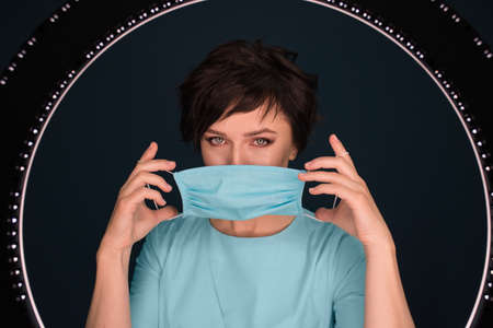 Medical worker, woman, wearing a protective mask while standing on a dark backgroundの写真素材