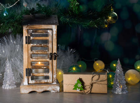 New Year's night decor with a gift under the tree, with a candle and garlands