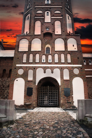 the main gate of the entrance to the tower of the castle Mir against the background of a colorful sunsetの写真素材