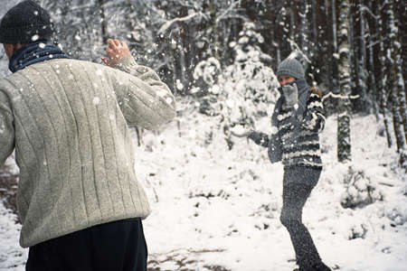 people play snowballs in winter forestの写真素材