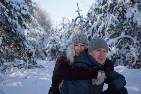 happy couple hugging on a walk in the snowy forestの写真素材