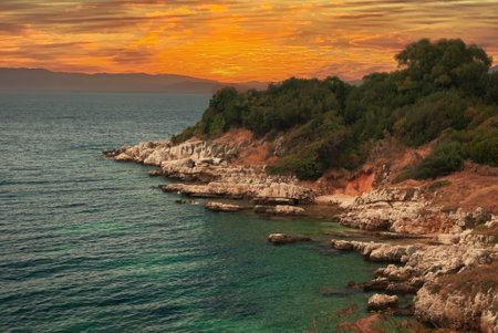 bright hot fiery sunset on the rocky coast of the Greek islandの写真素材