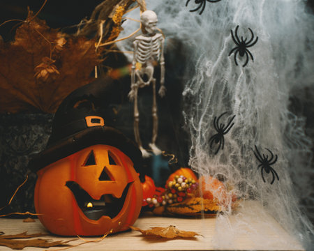 Halloween decoration, pumpkin with candles on the table, skeleton and cobweb backgroundの写真素材