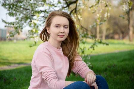 cute red-haired girl smiling while sitting in a blooming garden