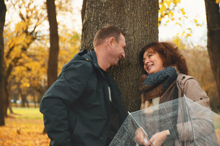 happy married couple over 50 years old, walking in the park in autumn on a warm sunny day, flirting, communicating, smiling, spending a day off together.の写真素材