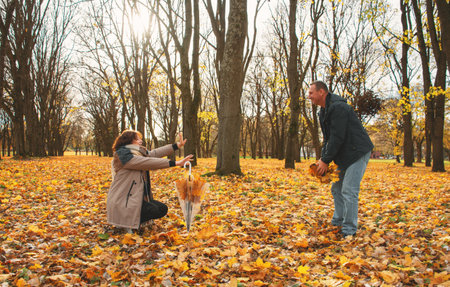 a married couple over 50 years old, walking in the park in autumn on a warm sunny day, playing with...
