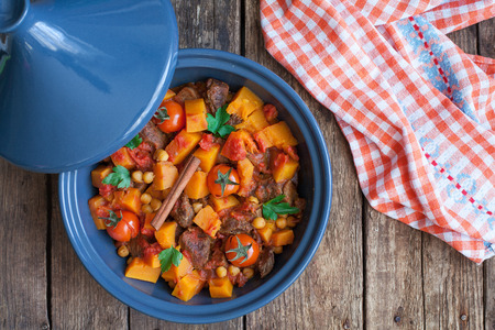 Moroccan Tagine with beef, chickpeas,  pumpkin and cherry tomatoes on a wooden table. Selective focusの素材 [FY31047543904]