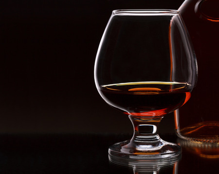 Glass of whiskey with bottle, on dark background, selective focus on the glass with place for text
