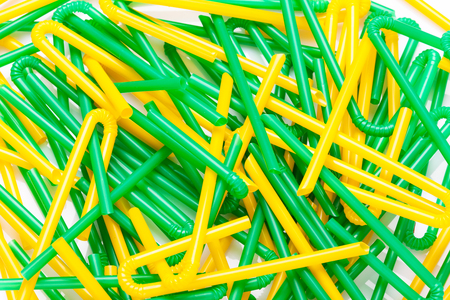 Chaotic pile green and yellow cocktail straws on white backgroundの写真素材