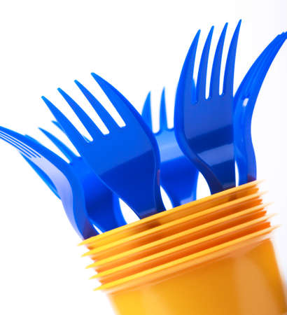 Bright plastic tableware, yellow cups and blue forks on white background, selective focusの写真素材