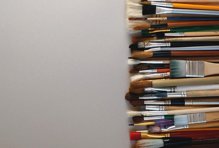 From above pile of assorted paintbrushes placed on gray background with copy space. Used paint brushes. Horizontal layoutの写真素材