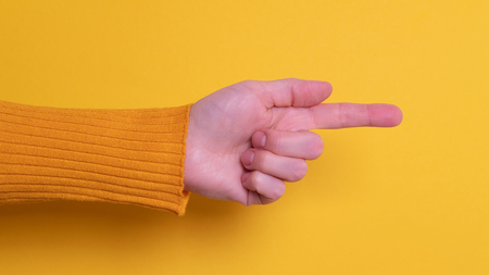 Beautiful woman hand pointing with her index finger on yellow bright backgroundの写真素材