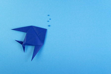 Origami tropical fish on sky blue minimalistic background. Paper sea fish and bubbles under water backdrop concept. Hobby, leisure, pastime. Underwater life, fauna creative craft work flat layの写真素材