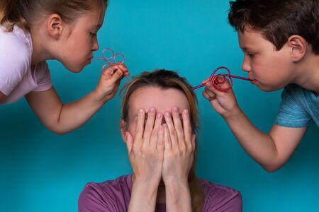 Tiredness from children. Daughter and son suck brain using plastic tubing. The problem of raising children. Family relationships. Stress conceptの写真素材