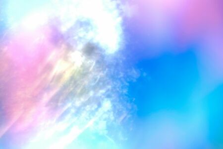 Bright abstract sky with glare background. Colorful pink, blue and white blurry backdrop. Sun flare, shining vibrant wallpaper. Rainbow clouds with sunlight creative horizontal imageの写真素材