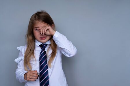 Small schoolgirl covering face, crying portrait. Preteen stressed, scared child hiding, wiping off tears. Pupil, student in school uniform. Back to school, sad, miserable young girl ready for classの写真素材