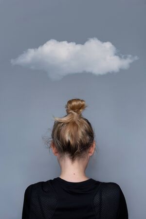 Young girl simple hairstyle back view with cloud over her head. Fashionable and simple hairdresser work. Fashion model, trendy woman. Hair in top bun close-up photo. Mental health metaphor conceptの写真素材