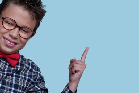 Young schoolchild pointing up portrait. Preteen schoolboy with glasses, gesturing at ceiling. Happy...