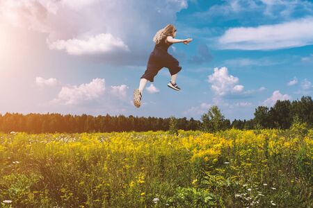 Cute girl jumping funny in clouds above earth. Happy small cheerful girl walking through. Levitation conceptの写真素材