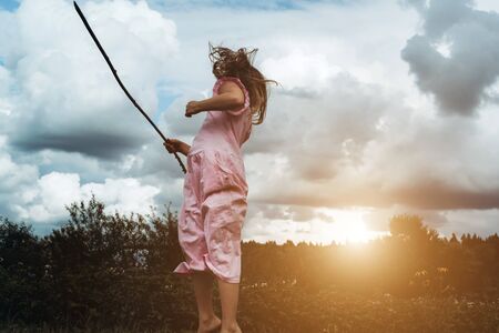 Happy girl rejoices summer. Young child playing outside. Summertime day activity. Happy, joyful kid outdoors. Having fun alone. Beautiful, scenic forest landscape. Picturesque sceneryの写真素材
