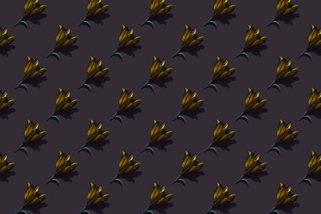 Pattern of golden lilies on dark background trend flat lay concept with fashionable toning. Many...