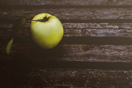 Fresh apple on dark rustic wooden bench. Background with copyspace. Shabby texture backdrop. Greenery bunch on dark wood planks. Botanical vintage wallpaperの写真素材