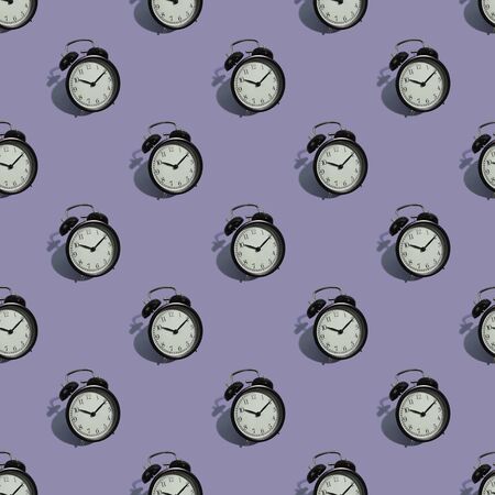 Many black classic style alarm clock with hard shadow isolated on purple background. Smile time...