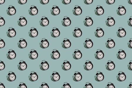 Many black classic style alarm clock with hard shadow isolated on green background. Smile time concept. Patternの写真素材