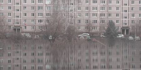 Many windows on apartment house in small town with reflection. Gray dull background. Local lifestyle and architectureの写真素材