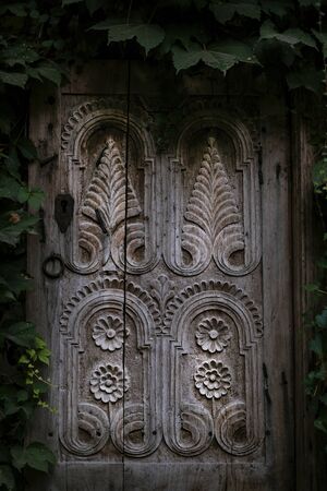 Wooden window platband with beautiful ornament surrounded by green plants. Stock photography. Nature...