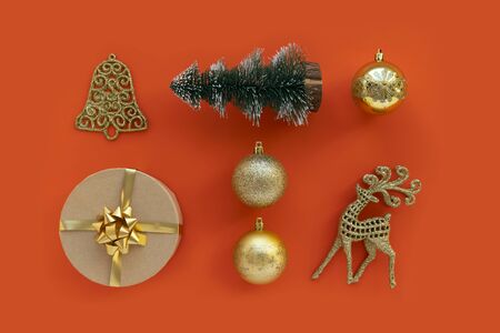 New Year gold decoration on red background. Winter holidays concept. New Year and Christmas gift, ball, green tree, bell and deer. Flat lay view.の写真素材
