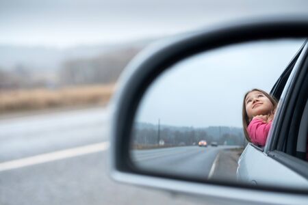 Young girl ride car and look out open window. Trip and responsible travel concept Teenager lifestyle. Childhood memories. Family time and road trip. Stock photo.の写真素材