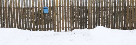 Snow field or street and old fence with blue postbox . Great background with copyspace. Winter and snow landscape. Stock photo.の写真素材