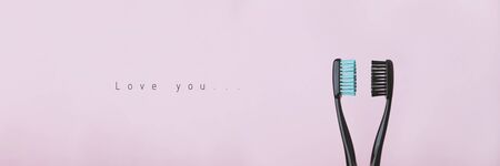 Two black toothbrushes on pink. Relationship between man and woman, Valentines Day and love concept. Banner with copyspace and text. Stock photo.の写真素材