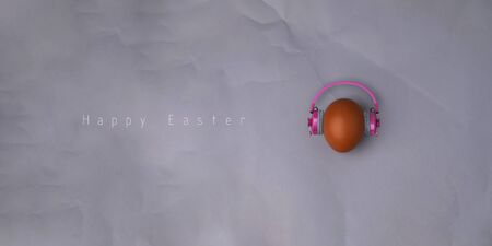 Easter egg with pink headphones on gray background with copyspace and text. Banner of macro moody minimalistic decoration concept. Stock photo.の写真素材