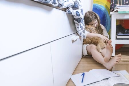 Girl study at home with red cat. Home education. Quarantine, self isolation, depression, mental health, social distance concept. Stock photo.の写真素材